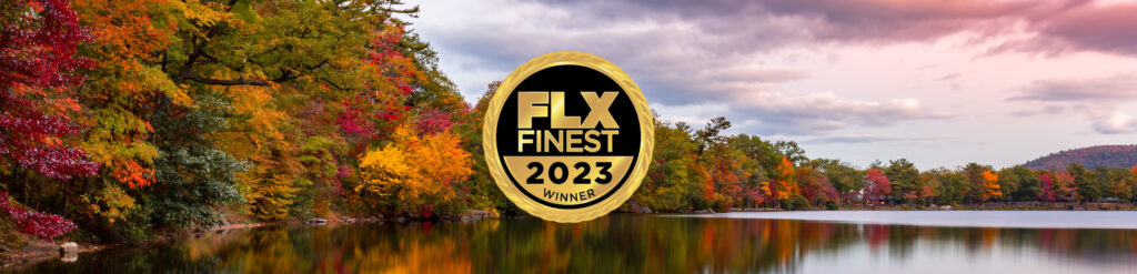 A serene lake mirrors vibrant autumn foliage under a cloudy sky, crowned by the prestigious "FLX Finest 2023 Winner" badge on the left side.