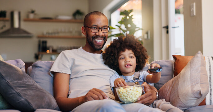 A smiling man and child sit on a couch at home, sharing a bowl of popcorn. Enjoying Empire Access Residential, the child holds a remote as they watch TV together in their cozy, well-lit living room.
