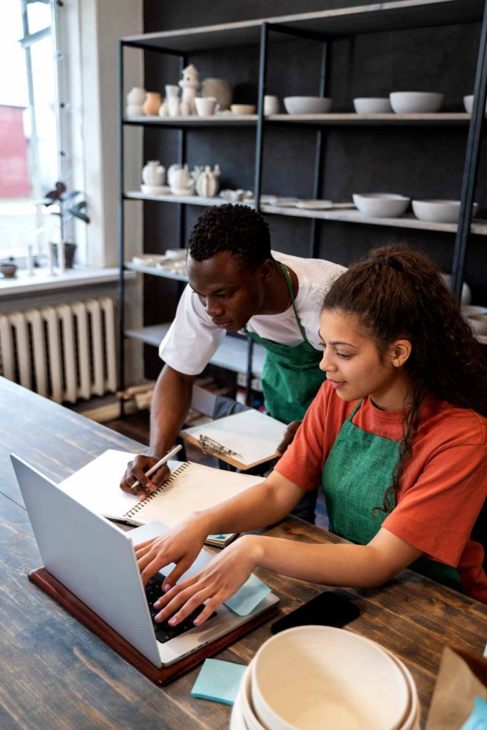 a man and woman looking at a laptop while working together in a business