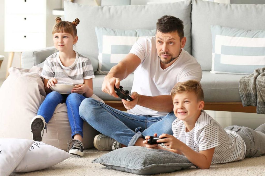 Father and two children playing video games together