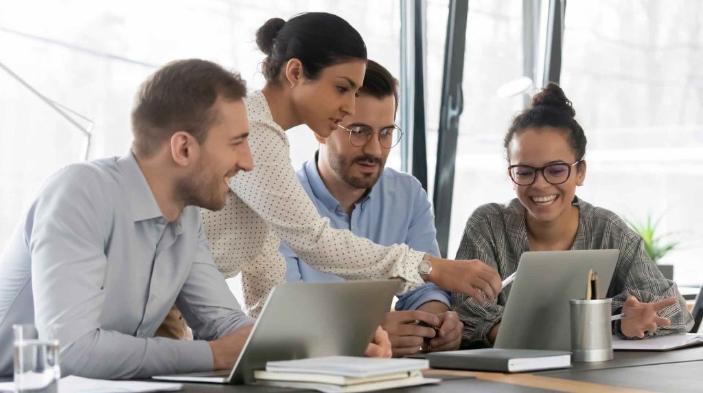 group of professionals working together at a table with a laptop