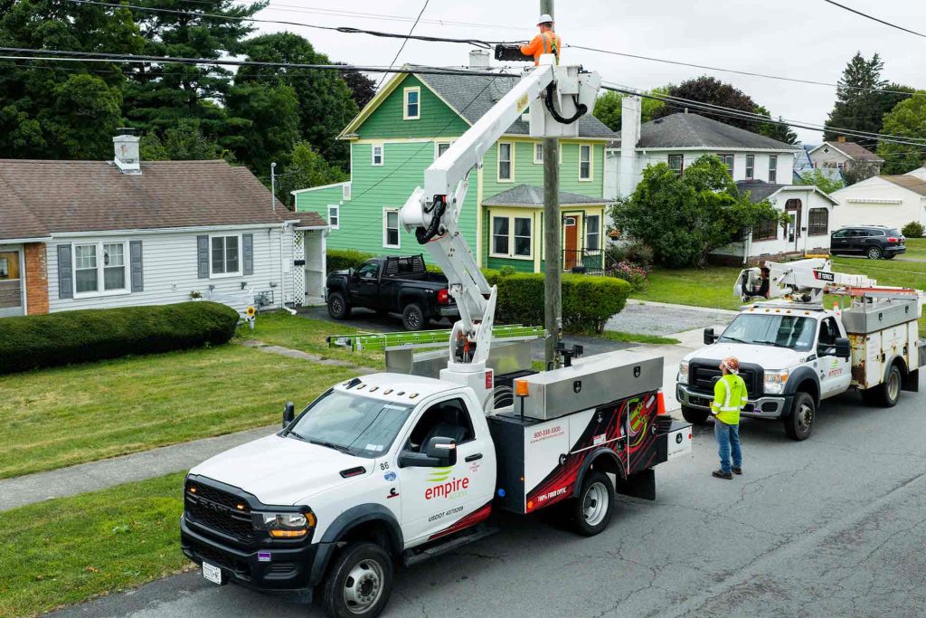 view of Empire Access employees installing Fiber lines by hanging them on existing utility poles